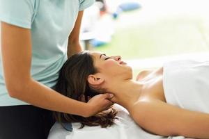 jeune femme souriante recevant un massage de la tête dans un centre de spa. photo