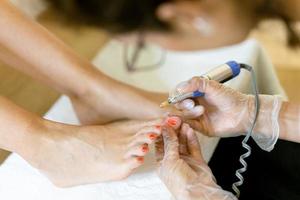 esthéticienne donnant une pédicure peignant les ongles de son client dans un centre de beauté.