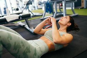 jeune sportive sur tapis de yoga faisant des redressements assis dans une salle de sport. photo