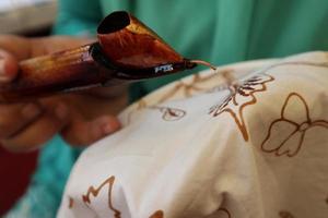 fermer la main pour faire des tulis batik sur le tissu avec canting photo