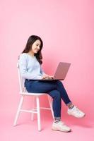Portrait de belle fille asiatique assise sur une chaise, isolée sur fond rose photo