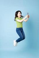 Portrait de belle jeune fille asiatique sautant, isolé sur fond bleu photo