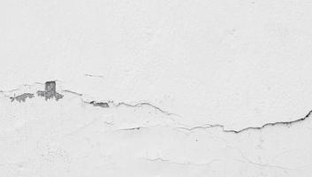 une photo d'un mur blanc fissuré du bâtiment. un mur usé pour une collection de textures de fond de construction.