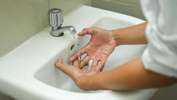 se laver les mains dans l'évier blanc pour garder sa main propre et stérile. retirer des bactéries attachées. photo