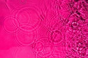 eau ondulante calme abstraite de la texture des gouttes de pluie de couleur rose. un motif de fond de l'eau liquide claire pour un design créatif. photo