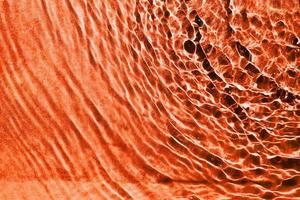 l'eau ondulante rugueuse de la texture du coin supérieur droit de couleur orange. un motif de fond de l'eau liquide claire pour un design créatif. photo