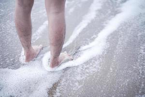 profitez du doux clapotis des vagues de mousse pieds nus. aller à la plage pour profiter du temps des vacances en se relaxant dans l'eau de mer et les plages de sable.