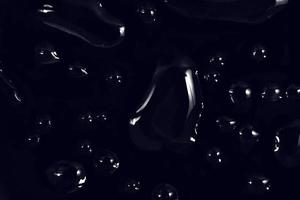 gouttes d'eau sur fond noir. gouttelettes d'eau de rosée abstraites sur une vitre pour un effet de superposition de photos ou pour donner un effet frais sur la maquette de boissons. plan macro sur la goutte de pluie détaillée.