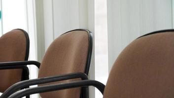 un agencement minimal des biens de bureau. les fauteuils marrons disposés à côté de la fenêtre à rideau. une chaise confortable dans la chambre.