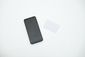 un smartphone noir vierge est à côté de la carte blanche vierge sur le tableau blanc. une source graphique pour la maquette. photo