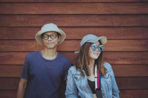 couples asiatiques portant des vêtements chapeau et mode de vie décontracté debout contre un mur en bois photo