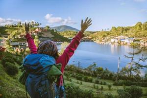 fille avec support de sac à dos avec impatience sur la belle vue sur le lac. voyageur touristique regardant la lumière du soleil sur les montagnes en voyage à mae hong son, en thaïlande. photo