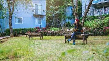 la fille a souri et était contente du livre qu'elle a lu. lire un livre dans le jardin fleuri. photo