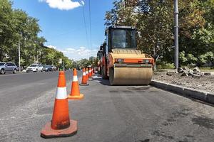 les cônes de route orange protègent les compacteurs sur roues lourds le long du bord de la route de la ville