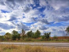 le paysage de la route contre le ciel bleu et les nuages d'orage qui se rassemblent un jour d'été. photo