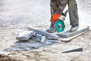 le constructeur utilise une meuleuse et un disque de coupe diamanté pour couper les blocs de granit. photo