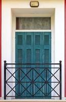 vieilles portes de balcon en bois vert avec volets en bois et barres métalliques dans le balcon de style grec.