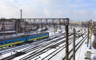 les wagons de chemin de fer de passagers roulent le long des voies ferrées en hiver dans le contexte du paysage urbain photo