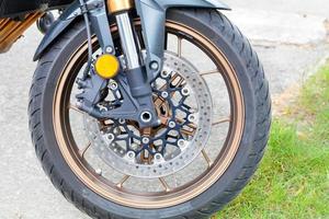 roue de moto sur fond d'asphalte et d'herbe verte en flou. photo