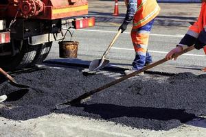 l'équipe de travail renouvelle une partie de l'asphalte avec des pelles en construction routière photo