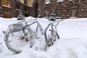 deux vélos enchaînés à un rack à l'extérieur sont couverts de neige lors d'une chute de neige photo