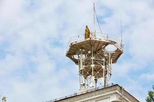 tour métallique sur le toit de la maison avec diverses antennes de communications cellulaires et satellites sur fond de ciel nuageux. photo