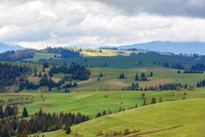 beau paysage de montagne des carpates printanières avec des nuages bas et des aperçus des rayons du soleil sur l'herbe verte fraîche. photo