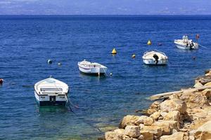 les bateaux à moteur et les bateaux sont ancrés le long de la côte rocheuse de la mer Ionienne. photo