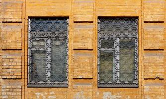 partie de la façade en brique d'une vieille maison de ville avec des barres en métal aux fenêtres. photo