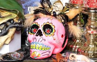 halloween, poupée de crâne rose avec du maquillage féminin et un chapeau avec des plumes isolées sur un arrière-plan flou. photo