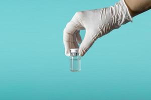 thème médical la main d'un médecin dans un gant médical blanc contient un flacon de médicament par injection ou de vaccin contre le coronavirus. vue de côté. pandémie 2021 photo