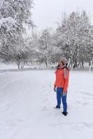 photo d'une belle femme heureuse et élégante dans une veste corail brillante et un jean bleu, souriante, profitant de la journée d'hiver.