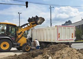 un tracteur de construction maniable charge des débris de construction dans un camion photo