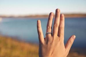 symbole de l'amour bien en vue sur la main de la jeune femme. rivière et herbes d'automne en arrière-plan. ciel bleu ensoleillé présent à l'horizon. photo