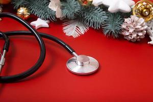 stéthoscope médical et décorations de Noël sur fond rouge. concept médical de noël