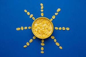 cornflakes avec du lait dans le bol jaune en forme de soleil sur fond bleu