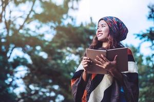 femme asiatique voyage nature. voyager se détendre. étudier lire un livre. éducation à la nature écrivez une note dans un parc public en été. en Thaïlande photo