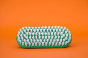 brosse de nettoyage verte sur fond orange photo