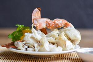 chair de crabe - pinces et pattes de crabe cuites sur assiette blanche et sauce aux fruits de mer sur la table , crabe bleu nageur photo