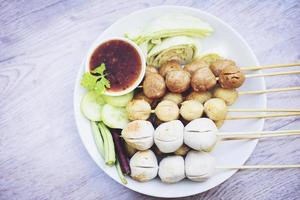nourriture thaïlandaise asiatique boulettes de viande grillées boulette de poisson et boulette de porc avec sauce épicée, boulettes de viande sur des brochettes sur assiette blanche et légumes frais cour de chou concombre de haricots longs photo