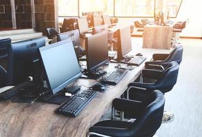 groupe d'ordinateurs avec moniteur soigneusement placé dans un laboratoire informatique, salle informatique dans le bureau moderne avec fenêtres photo