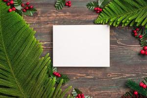 maquette de carte de voeux de noël avec feuille de pin et gui sur table en bois photo