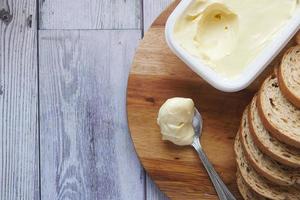 beurre dans un récipient en plastique et pain sur table photo