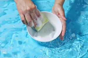 femme lave main bol en céramique dans l'eau. laver l'ustensile après utilisation. photo