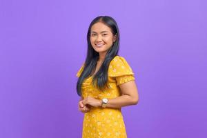 souriante jeune femme asiatique garde la main ensemble et se sent optimiste sur fond violet