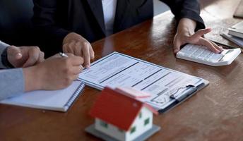 un courtier immobilier ou un agent d'assurance travaille avec des modèles de maisons et des contrats de vente de biens immobiliers au sein du bureau, une approbation de prêt hypothécaire, un prêt immobilier et un concept d'assurance. photo