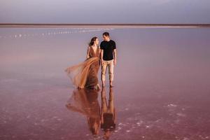 fille et un gars sur la rive d'un lac salé rose photo