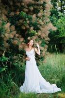 fille heureuse dans une robe longue turquoise dans un parc verdoyant photo