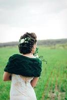 mariée avec un bouquet dans une robe ivoire et un châle tricoté photo