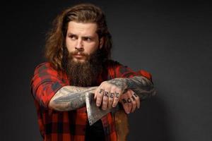 bel homme aux cheveux longs avec une hache dans les mains sur un fond de studio sombre photo